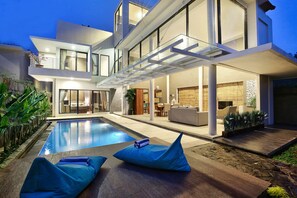 Une maison moderne à deux étages dotée d’une piscine, d’un espace salon extérieur et d’un patio.