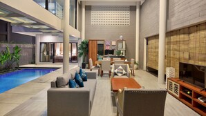 A spacious living area with a pool, modern furniture, and a television. - Bellevue Heritage Villas Nusa Dua (Nusa Dua)