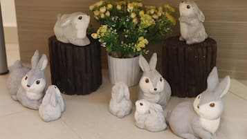 A collection of rabbit figurines on wooden stumps and a potted plant with yellow flowers.