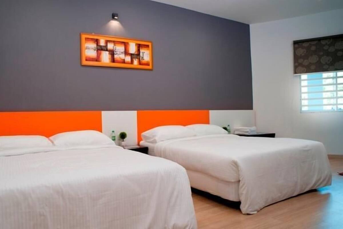 Een hotelkamer met twee bedden, een grijze accentmuur en een kunstwerk erboven.