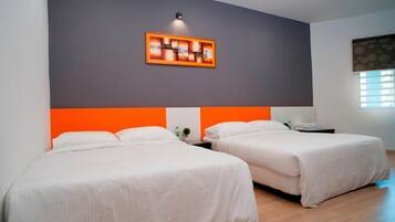 Habitación de hotel con dos camas, una pared de acento gris y una obra enmarcada sobre las camas.