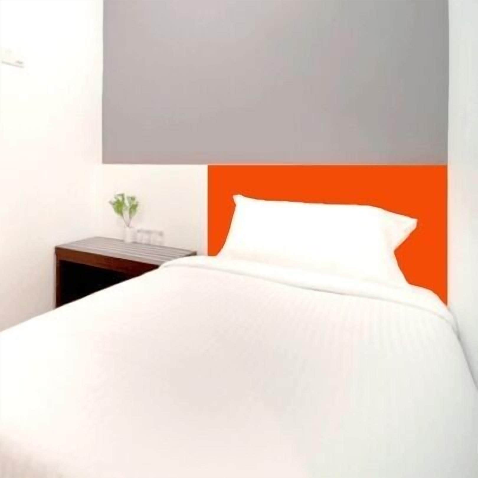 Een hotelkamer met een bed, nachtkastje en een aan de muur bevestigde televisie.