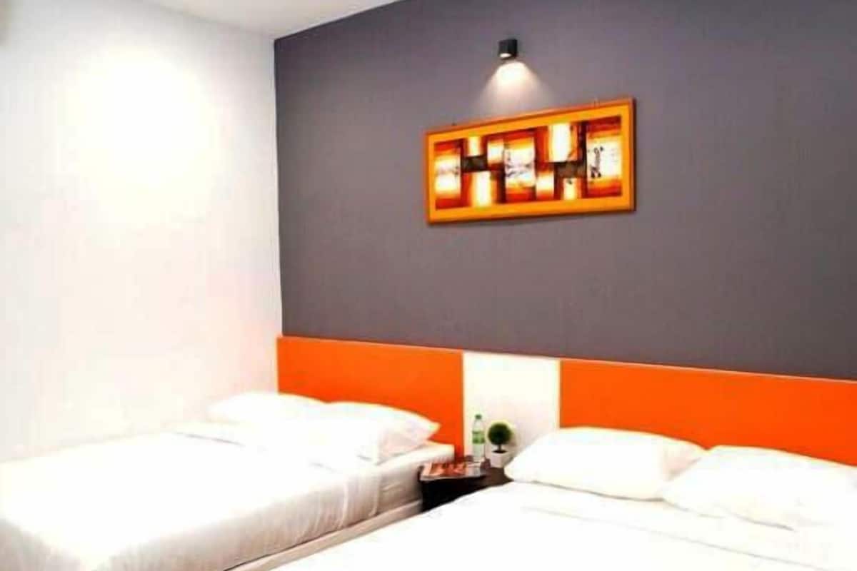 Een hotelkamer met twee enkele bedden, een grijze accentmuur en een kunstwerk erboven.