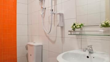 Un baño con inodoro, bidé, lavabo y repisa de vidrio con flores.
