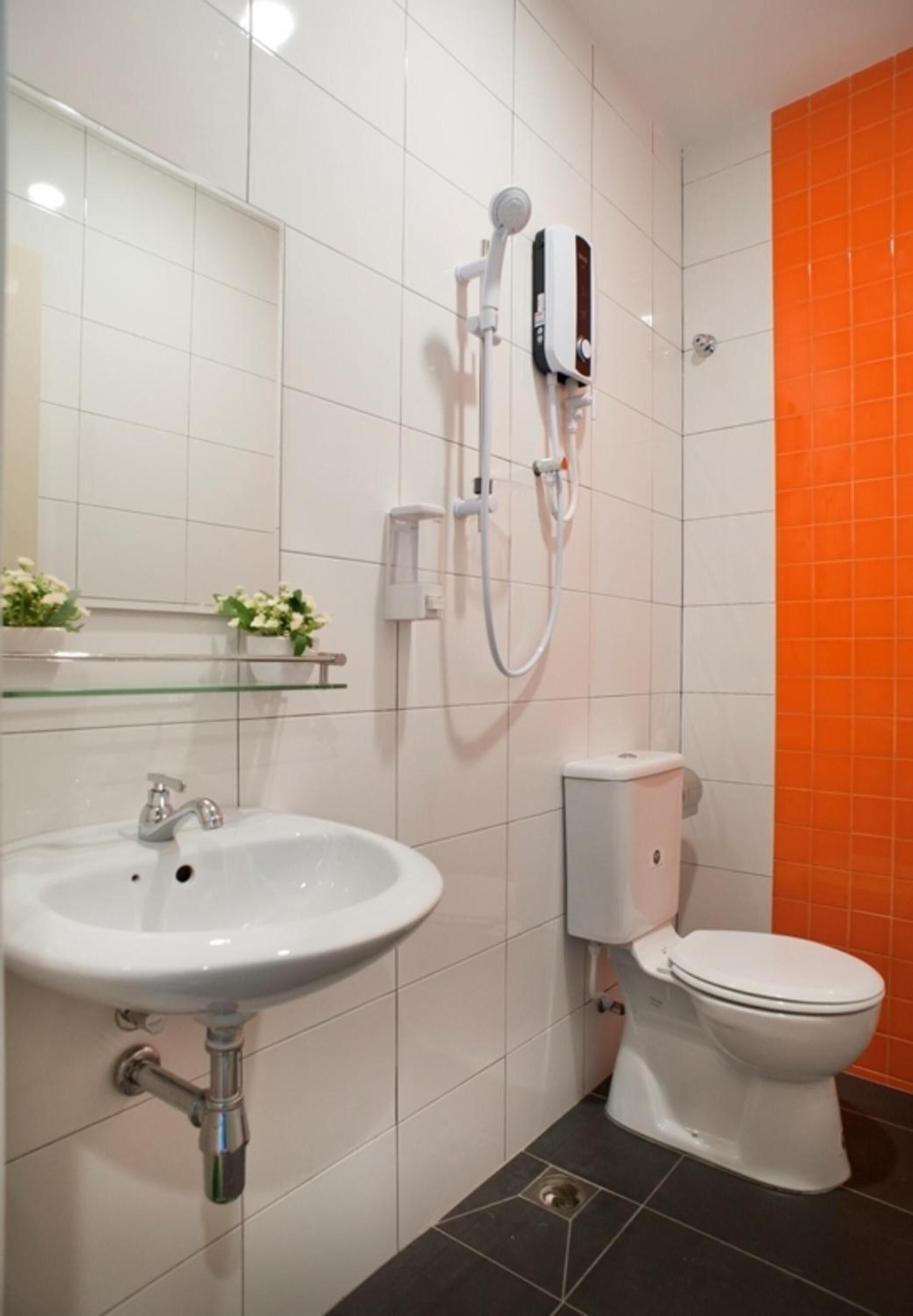 A bathroom with a white sink, a toilet, and a shower unit.
