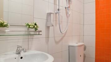 Ein Badezimmer mit einem weißen Waschbecken, einer Glastrennwand mit Blumen, einer weißen Toilette und einer Dusche mit Duschschlauch.