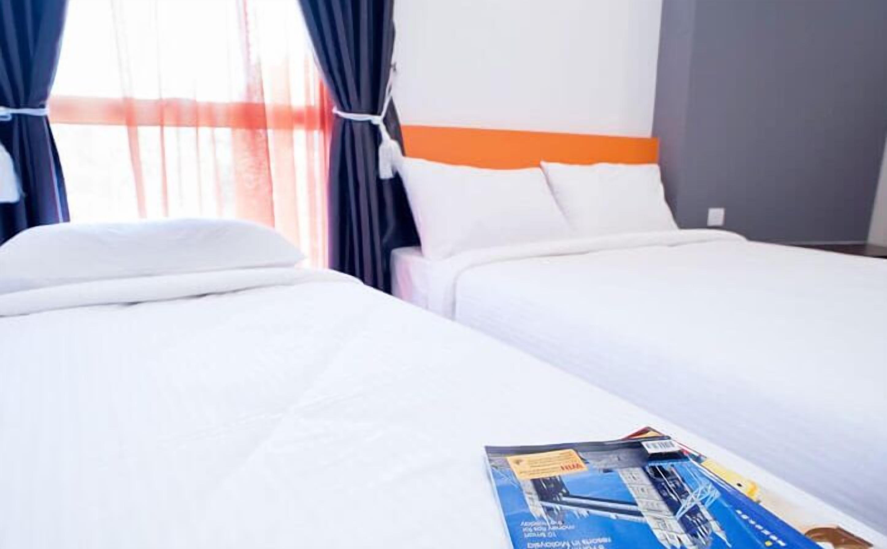 A hotel room with two beds, white bedding, and a window with curtains.