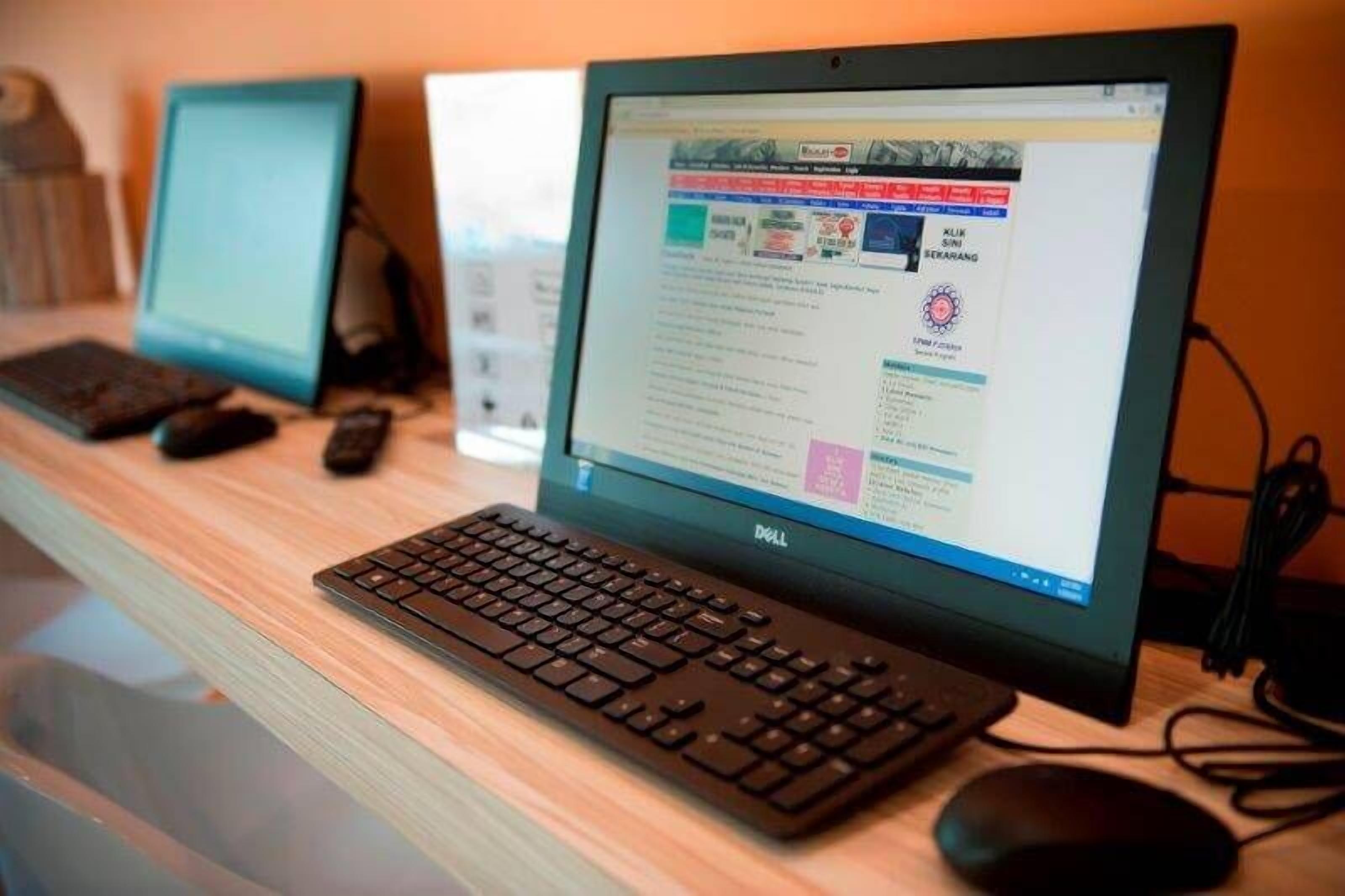 A computer setup with a keyboard and monitor on a wooden desk.
