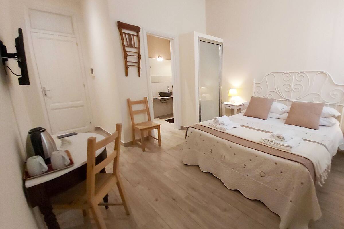 A bedroom with a bed, bedside tables, a chair, a desk, and a mirror.