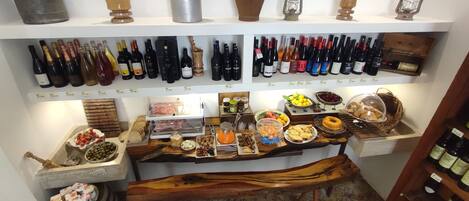 A wine cellar with shelves of wine bottles, a wooden counter with food items, and antique kitchenware.