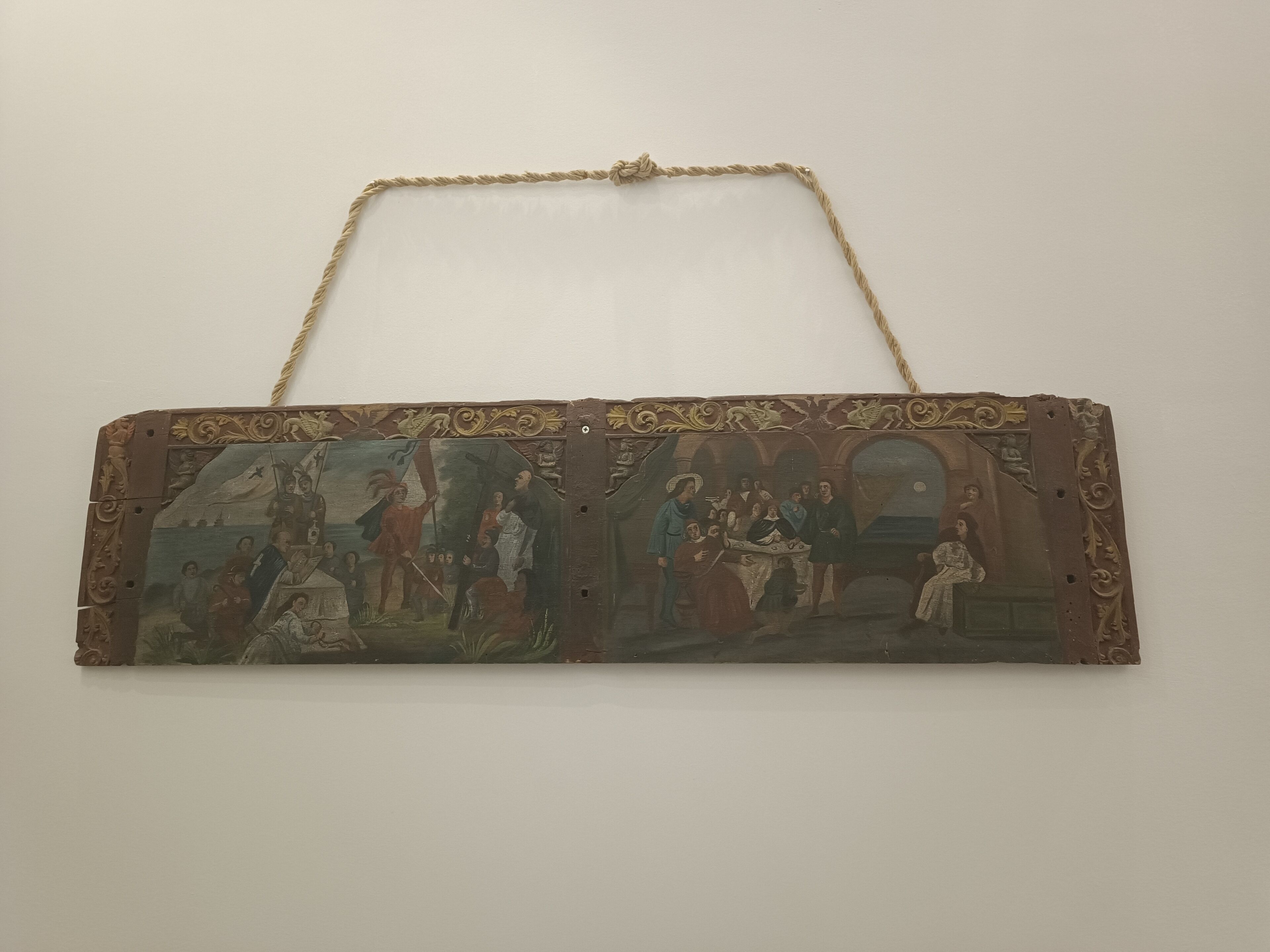 A rectangular, ornate handbag with a chain strap, featuring a detailed painted scene.
