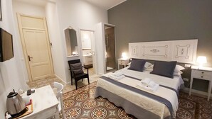Habitación de hotel con cama, escritorio con teléfono, silla, espejo y puerta de baño.