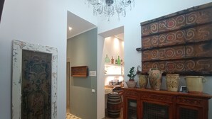 Un pasillo con piso estampado, un mueble de madera con puertas de vidrio y un panel decorativo en la pared.