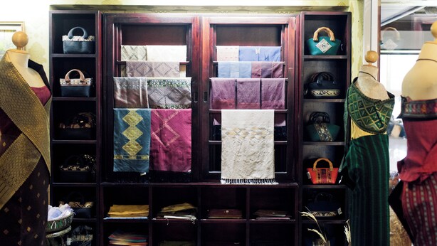 A display of patterned textiles and handbags on shelves and mannequins. - Champasak Grand Hotel (Pakse)