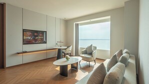 Un salon moderne avec un canapé, une table basse, un téléviseur et une grande fenêtre.