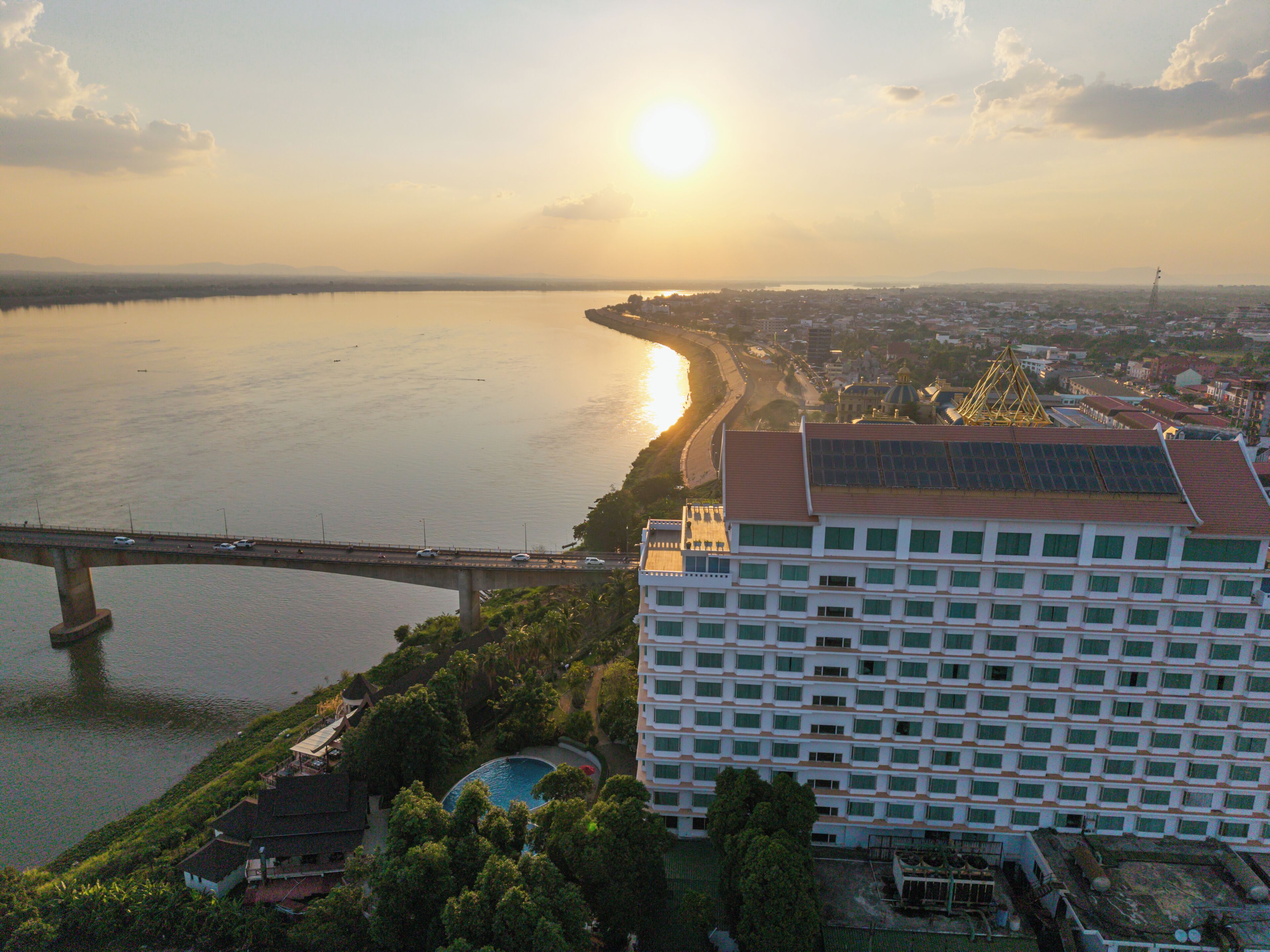 A high-rise building with a swimming pool, a bridge, and a body of water.