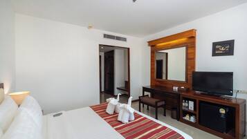 A hotel room with a bed, a desk, a television, and a mirror.