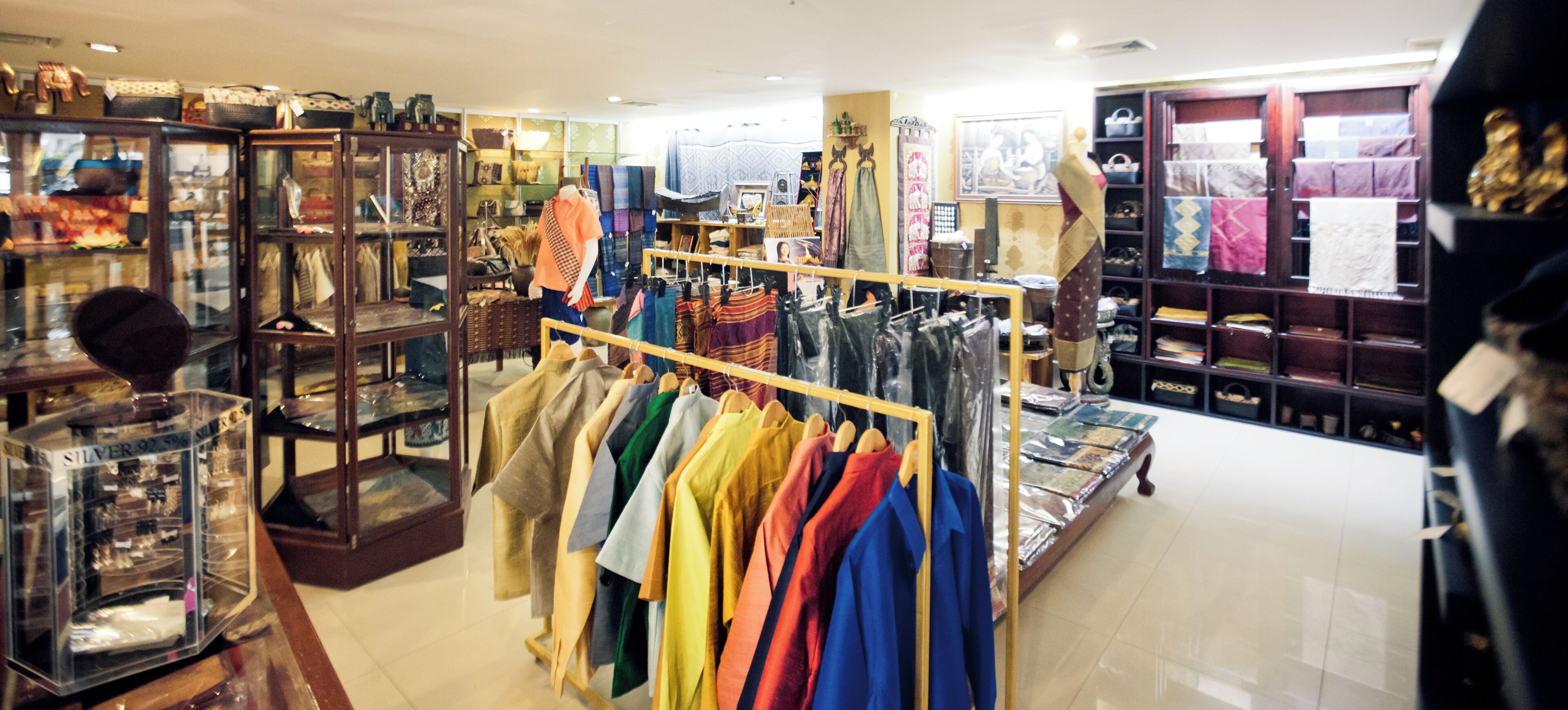 A clothing store with racks of colorful garments, glass display cases, and shelves with various items.