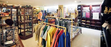 A clothing store with racks of colorful garments, glass display cases, and shelves with various items.