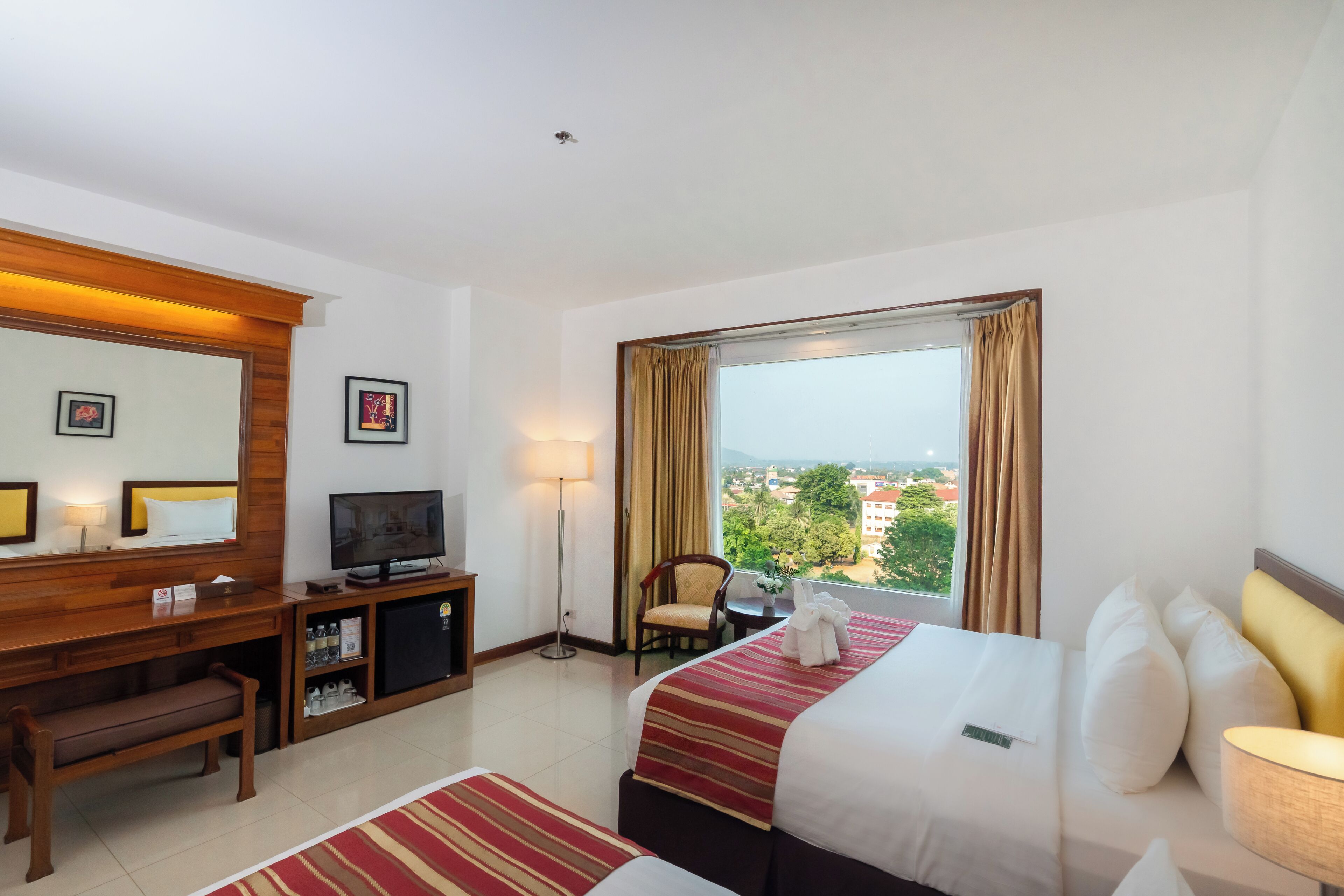 Habitación de hotel con cama, escritorio con televisor, una silla y vista a la ciudad.