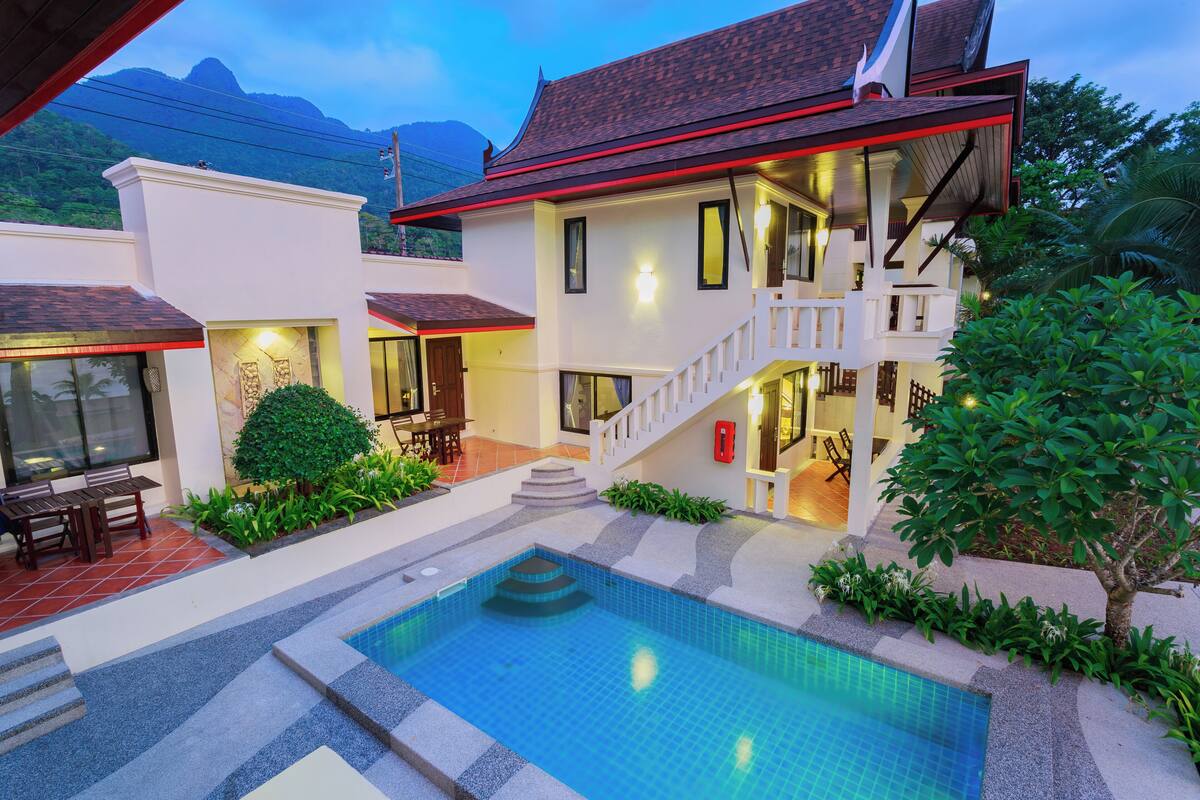 A two-story house with a swimming pool, stairs, and a staircase leading to a balcony.