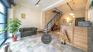A hotel lobby with a staircase, a reception desk, a potted plant, and a Christmas tree. - Discovery B&B (Hualien City)