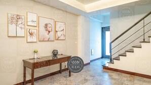 A hallway with a wooden console table, framed artwork, and a staircase. - Discovery B&B (Hualien City)