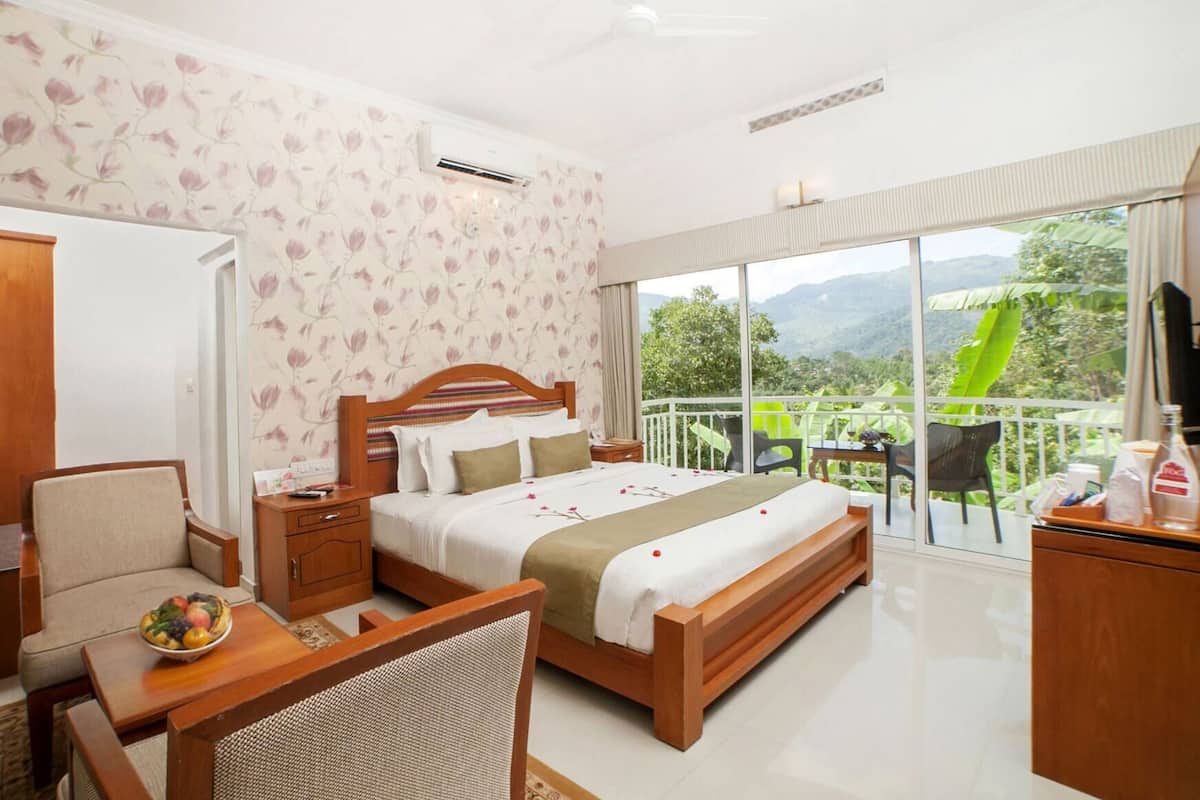 Ein Hotelzimmer mit Bett, Schreibtisch, Stuhl und einem Balkon mit Bergblick.
