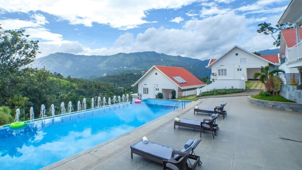 A swimming pool with lounge chairs and a view of mountains. - The Fog Munnar Resorts & Spa (Devikolam)