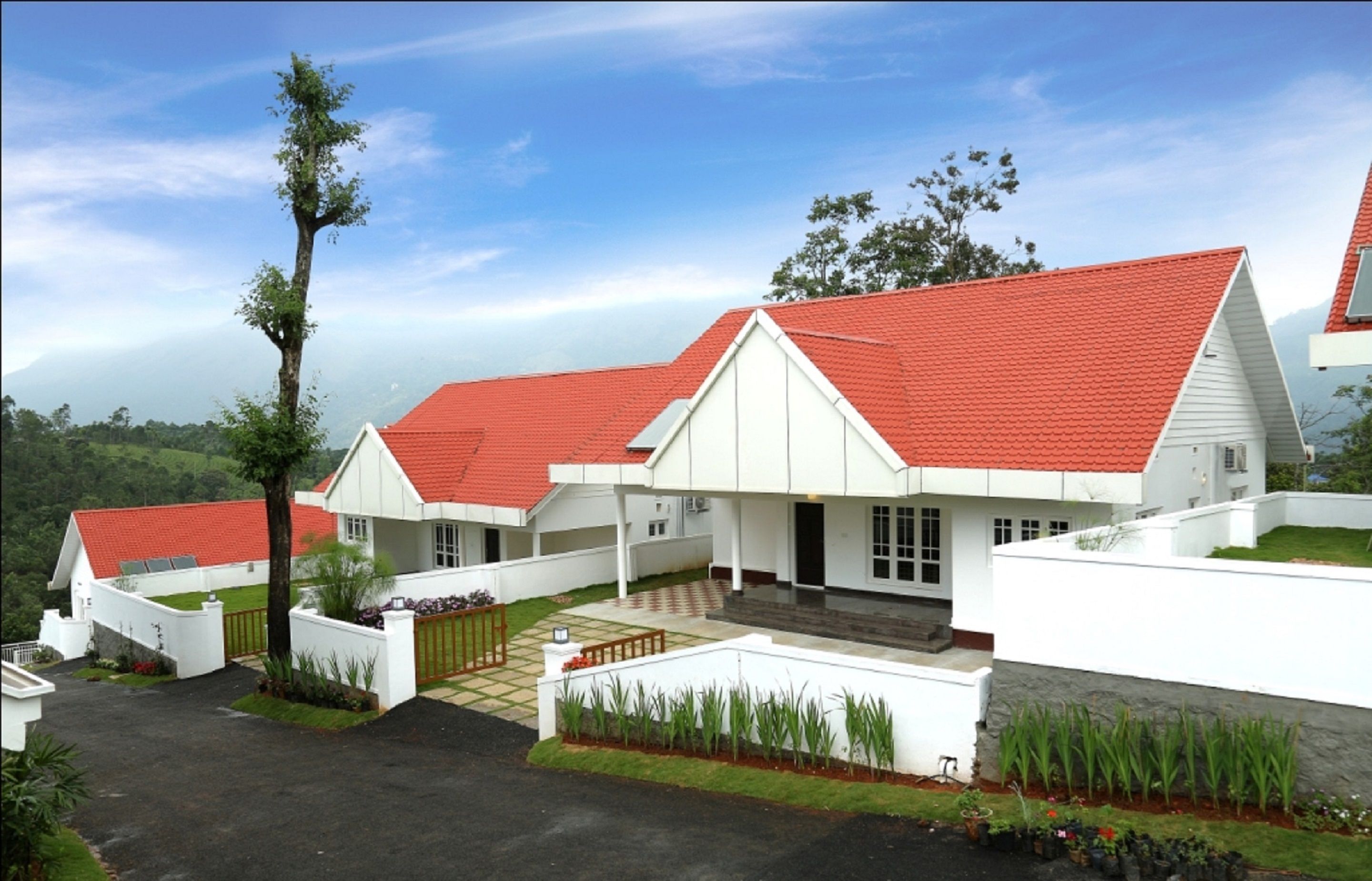 A white building with a red roof, surrounded by a well-maintained lawn and a few trees.