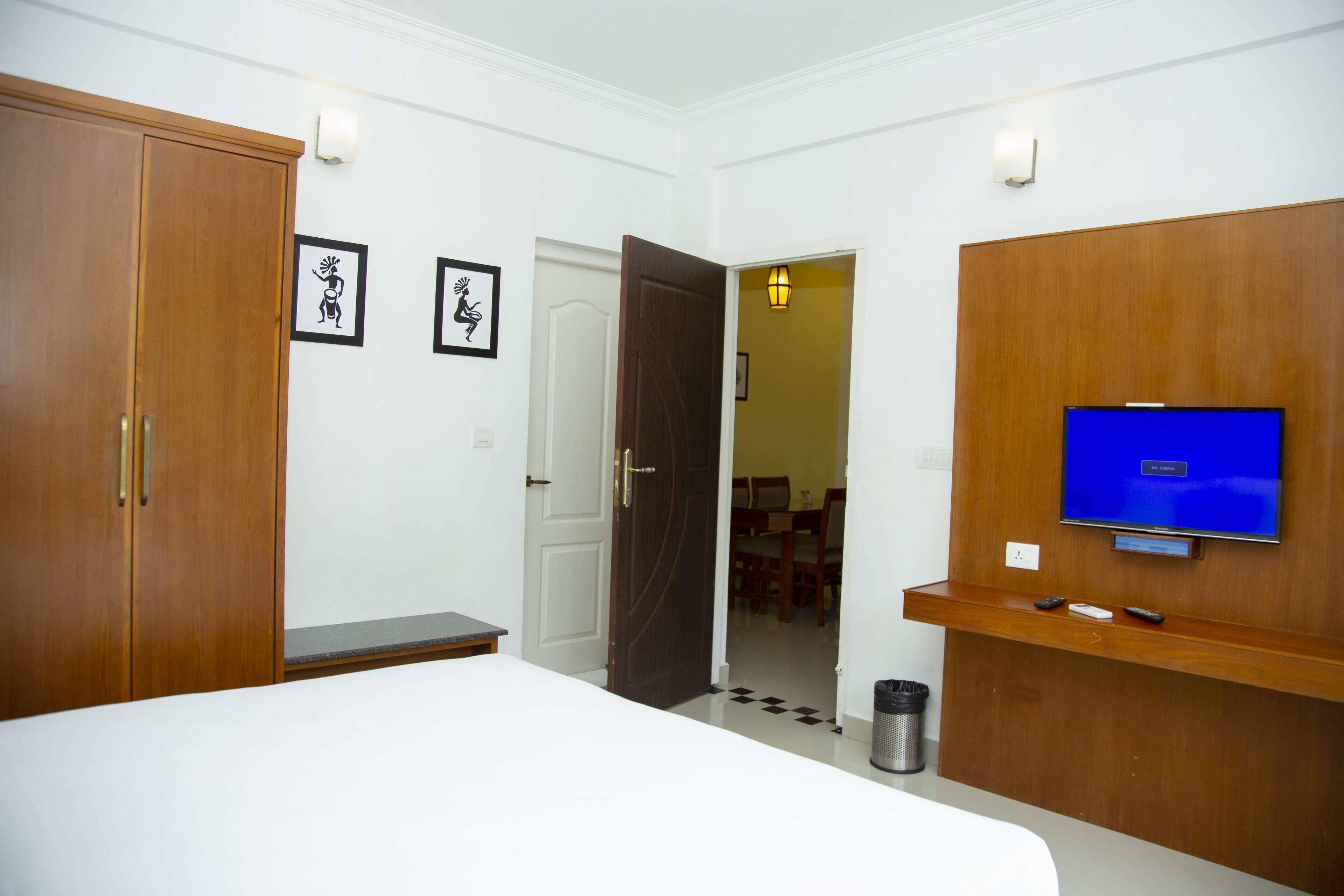 A hotel room with a bed, wardrobe, TV, and a small table.
