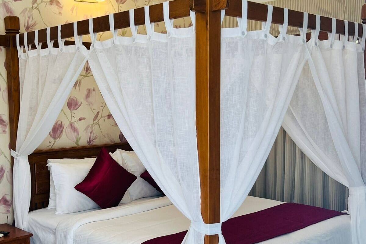 Ein Himmelsbett mit weißer Bettwäsche und einer roten Decke.