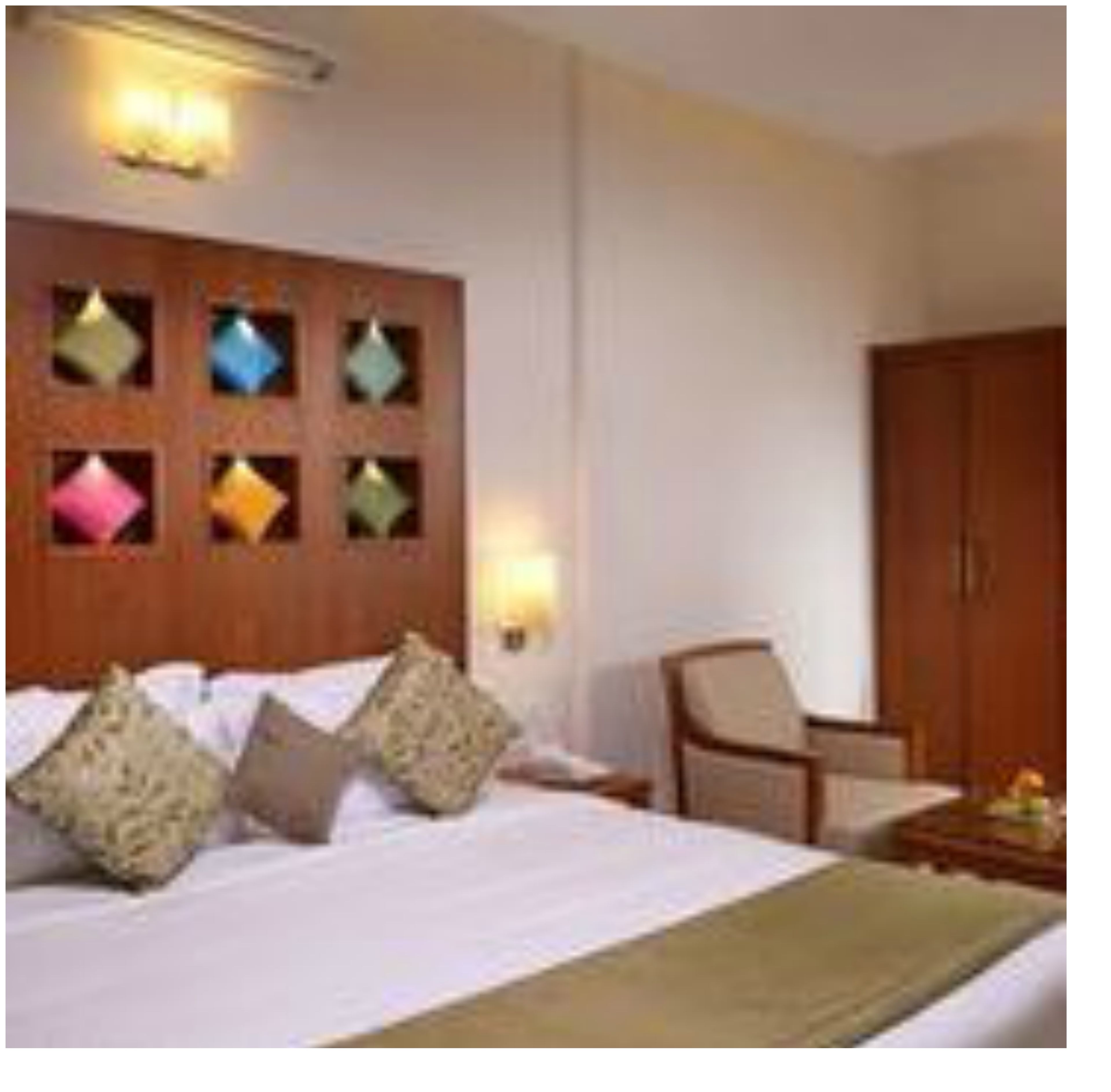 Una habitación de hotel con una cama, cabecera de madera con paneles decorativos, una silla y un armario.