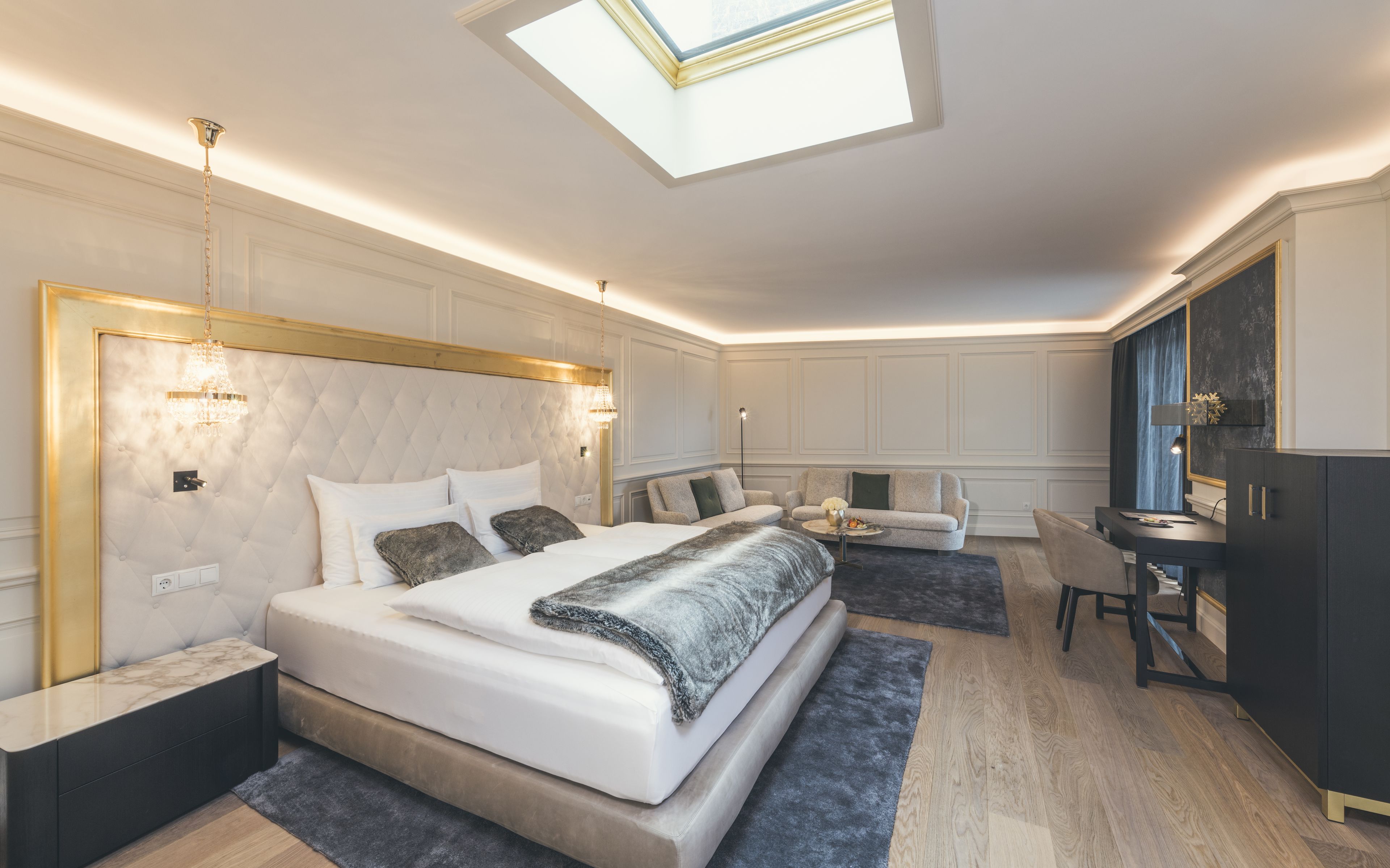 A modern bedroom with a large bed, a desk, and a chair.
