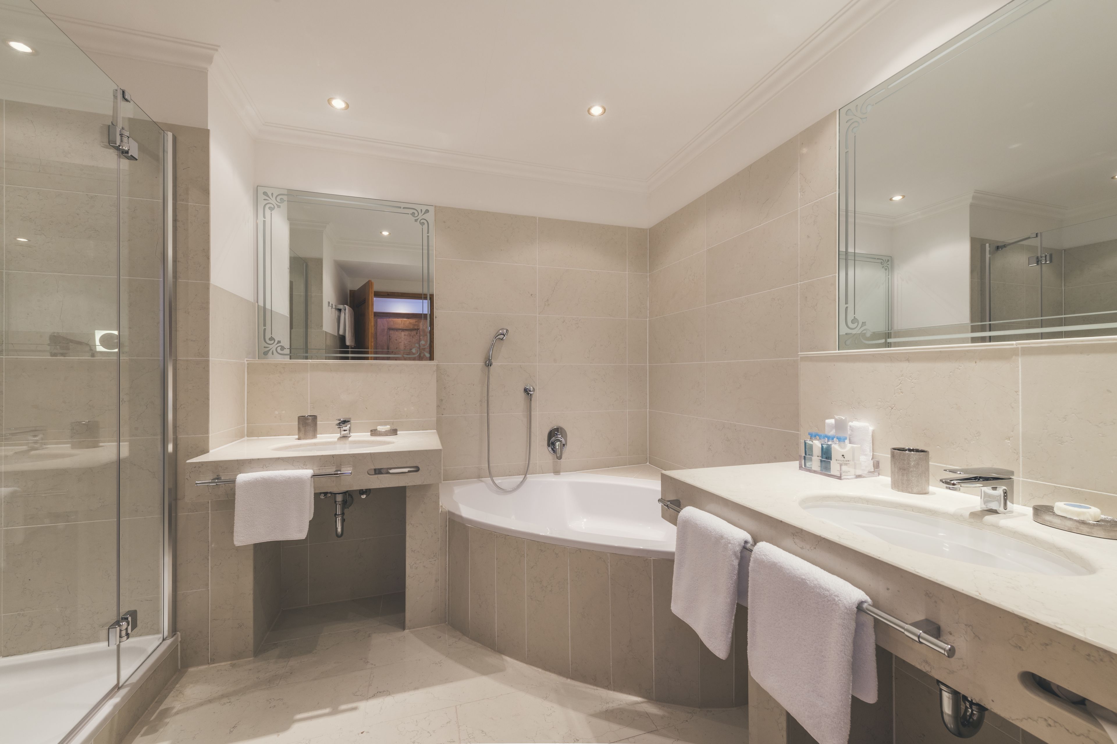 A modern bathroom with a glass-enclosed shower, a freestanding bathtub, and a vanity with a mirror.