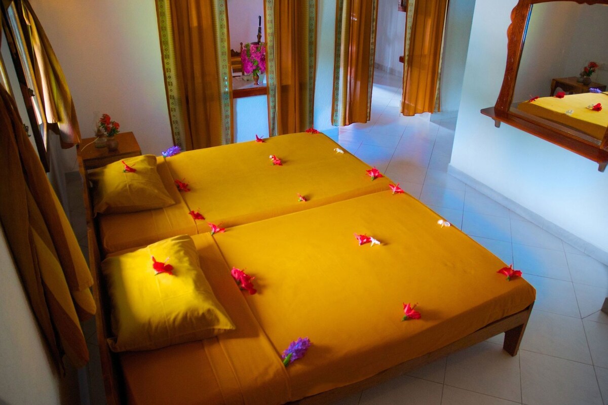 A room with two beds, a mirror, and curtains.