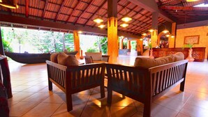 A spacious lobby with wooden benches, tiled flooring, and a high ceiling with exposed beams. - Eva Lanka Hotel (Morakatiyara)
