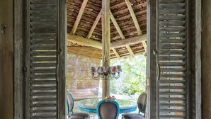 An open wooden door leading to a covered outdoor area with a table and chairs. - Casas da Vila (Porto Seguro)