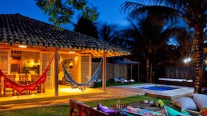 A cozy outdoor area with a hammock, a wooden bench, and a pool. - Casas da Vila (Porto Seguro)