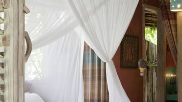 A bed with a white canopy in a room with a wooden ceiling and a hanging light fixture.