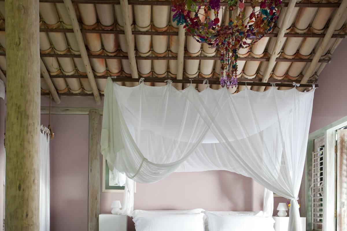 Ein Schlafzimmer mit Himmelsbett, Blumentopf und gemustertem Teppich.