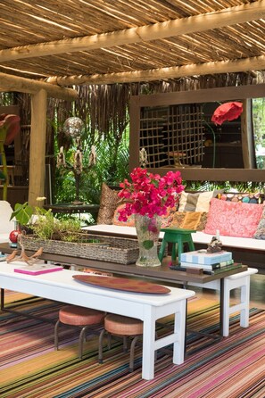 A cozy seating area with a woven ceiling, a white table, and a colorful striped rug. - Casas da Vila (Porto Seguro)