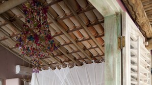 A bedroom with a canopy bed, a hanging decorative piece, and a patterned rug. - Casas da Vila (Porto Seguro)