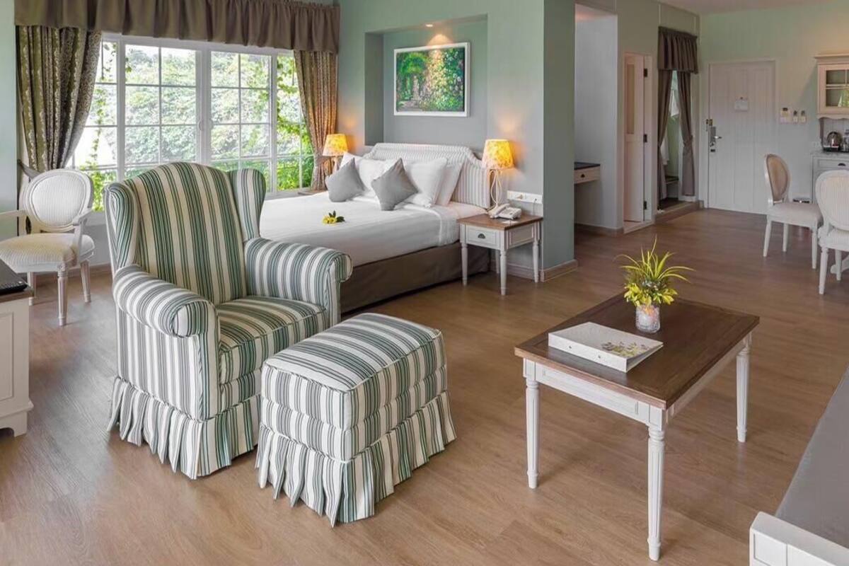 A room with a bed, a chair, a table, a desk, and a view of the outdoors.