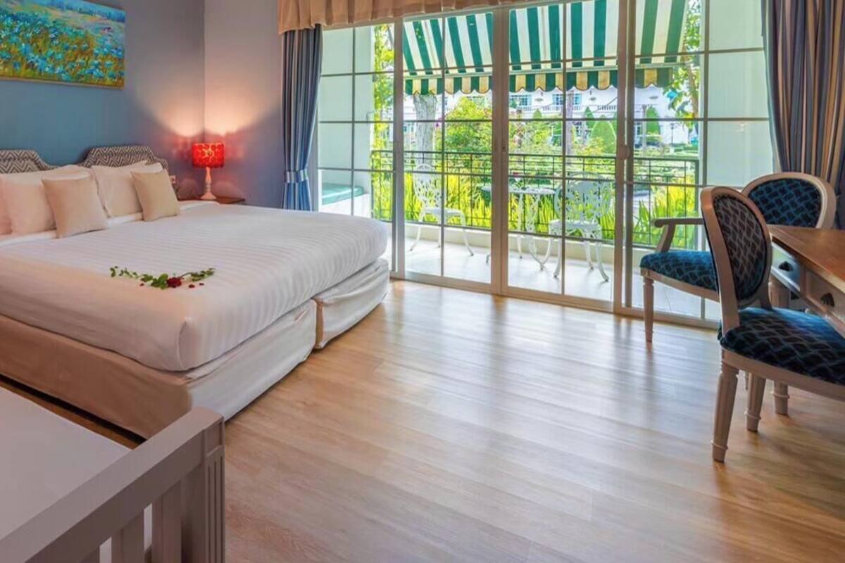 A hotel room with two beds, a balcony with a view, and a dining area.