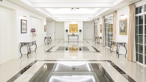 A spacious, well-lit hallway with a polished floor, framed artwork on the walls, and a central table with a decorative item. - Kensington English Garden Resort Khaoyai (Pak Chong)