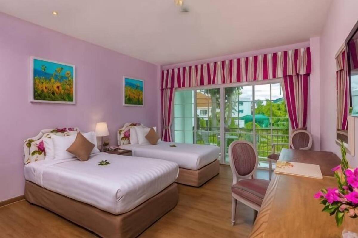A hotel room with two beds, a desk, and a chair.