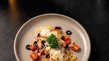 A plate of spaghetti with tomatoes, olives, and cheese.