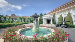 A fountain with a statue, surrounded by pink flowers, in front of a building labeled 'ENSINGTON'. - Kensington English Garden Resort Khaoyai (Pak Chong)