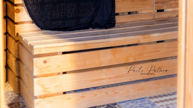 A person seated on wooden benches in a cabin-like setting. - Masseria Villa Marchesi (Taranto)